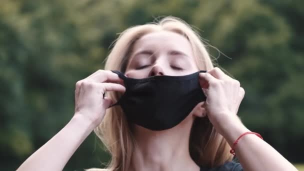 Mooi meisje zet een masker op haar gezicht op de natuur — Stockvideo