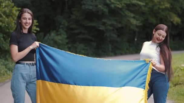 Dwie nastoletnie dziewczyny trzymające ukraińską flagę w naturze — Wideo stockowe