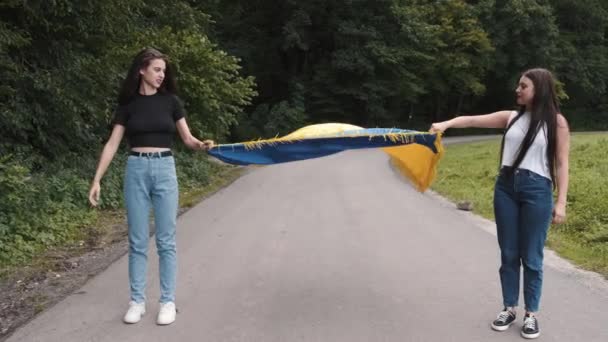 Deux adolescentes tenant le drapeau ukrainien dans la nature — Video