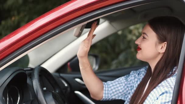 Mooie vrouw kijken naar auto spiegel en zetten bril op — Stockvideo