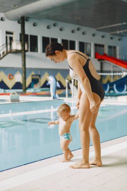 Anne ve küçük oğlu yüzme havuzunun yanında duruyor.