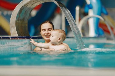 Anne ve küçük oğlu yüzme havuzunda yüzüyorlar.