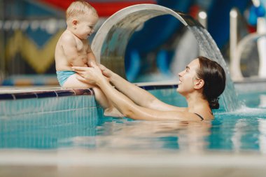Anne ve küçük oğlu yüzme havuzunda yüzüyorlar.