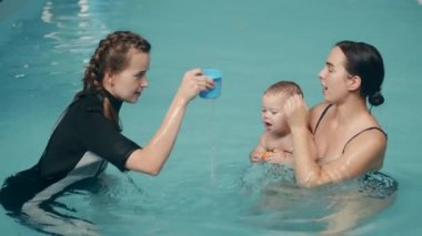 Anne ve oğul yüzme dersinde bayan eğitmenle.