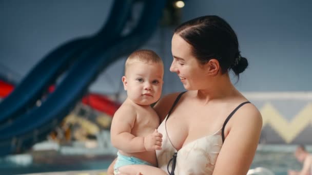 Mother hugging and kissing baby child at the swimming pool — Stock Video