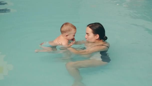 Mom teaches infant son to swim in the pool at water park — Stock Video