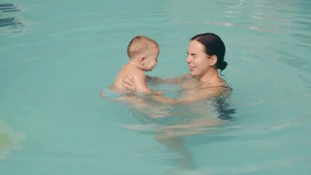 Máma učí kojence syn plavat v bazénu v aquaparku — Stock video