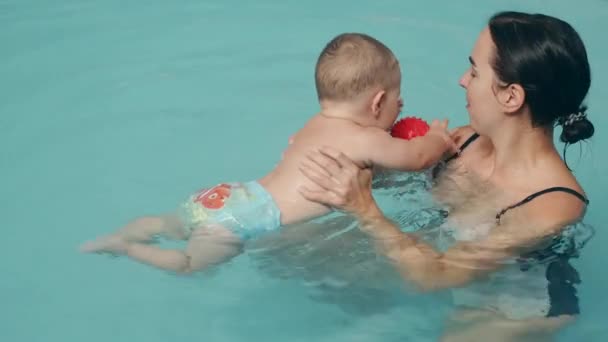Η μαμά διδάσκει τον μικρό γιο να κολυμπάει στην πισίνα στο θαλάσσιο πάρκο. — Αρχείο Βίντεο
