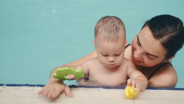 Kind mit Mutter schwimmt im Hallenbad am Rand — Stockvideo