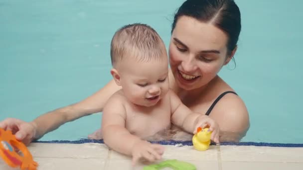 Παιδί με μητέρα κολυμπά στην εσωτερική πισίνα κοντά στο χείλος — Αρχείο Βίντεο