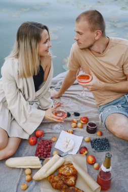 İnsanlar piknik setiyle suyun kenarında oturuyorlar.