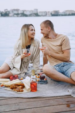 İnsanlar piknik setiyle suyun kenarında oturuyorlar.