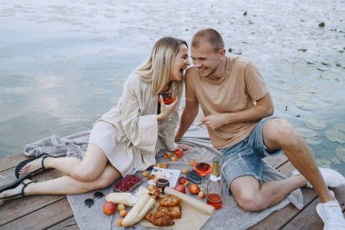 İnsanlar piknik setiyle suyun kenarında oturuyorlar.
