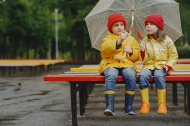 Yağmurlu bir parkta oynayan çizmeli komik çocuklar.