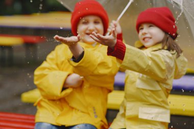 Yağmurlu bir parkta oynayan çizmeli komik çocuklar.