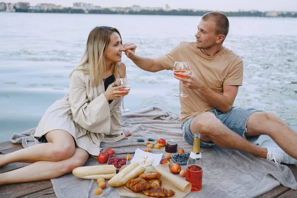 Persone sedute vicino all'acqua con set da picnic — Foto Stock