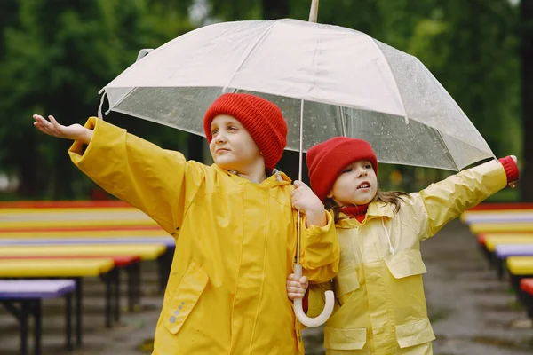 Lustige Kinder in Regenstiefeln spielen im verregneten Park — Stockfoto