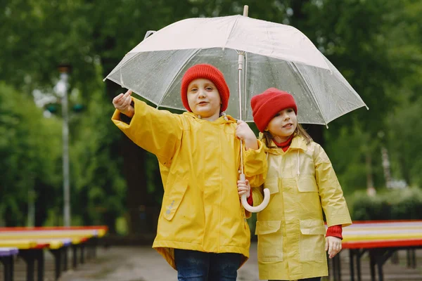 Забавные дети в дождевых сапогах играют в дождевом парке — стоковое фото