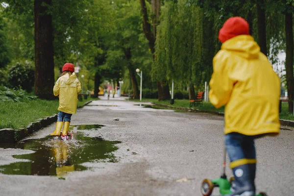 Bambini divertenti con gli stivali da pioggia che giocano con i pattini — Foto Stock