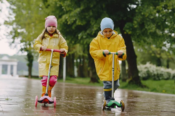 Смешные дети в дождевых сапогах играют на коньках — стоковое фото