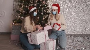 Tek kullanımlık maskeli iki güzel kadın içeride Noel 'i kutluyorlar.