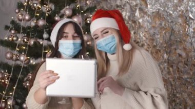 Kız arkadaşlar Noel 'i kutluyor ve tablette video çağrısı yapıyor.