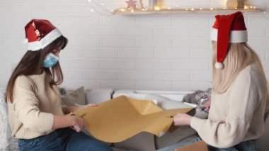 Noel hediyesini paketleyen iki genç kadın.