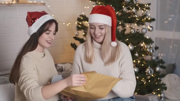 Две девушки упаковывают рождественский подарок — стоковое видео