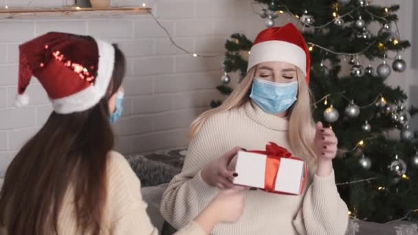 Две подруги женщины празднуют Рождество вместе во время пандемии коронавируса сидя у елки — стоковое видео