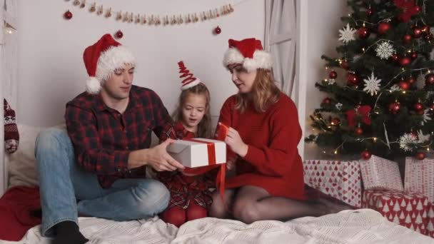 크리스마스를 축하하는 부모님들 크리스마스 트리 근처에 앉아 있는 딸과 함께 — 비디오
