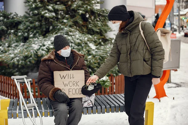 Disabled homeless man on crutches in old clothes