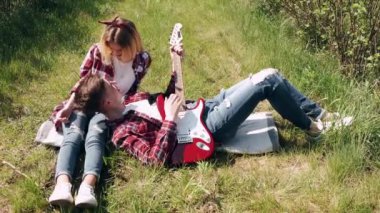 Erkek ve kadın bahar günü tarlada. Birbirine aşık çiftler bahar tarlasında vakit geçirir. Çimenler arka planda. Elektro gitarlı adam..