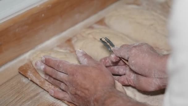 Las manos masculinas hacen cortes en la masa de pan con cuchilla — Vídeos de Stock