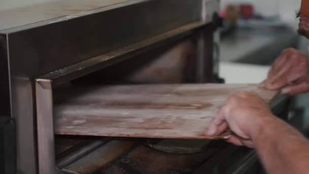 Шеф-повар кладет кусок хлеба в промышленную духовку 4к — стоковое видео