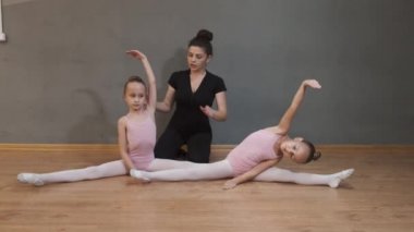Profesyonel balerin kızların esnemesine yardım ediyor.