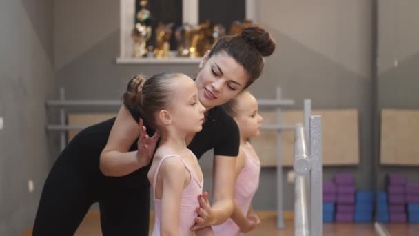 Jonge leraar onderwijzen kleine ballerina 's op een dansles in de studio — Stockvideo