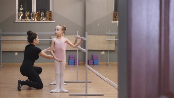 Ballettlehrerin professionelle Ballerina hilft Mädchen beim Training in der Nähe der Barre — Stockvideo