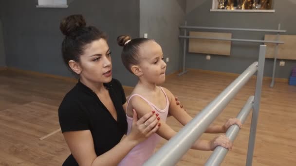 Balet učitel profesionální balerína pomáhá dívka vlak v blízkosti barre — Stock video