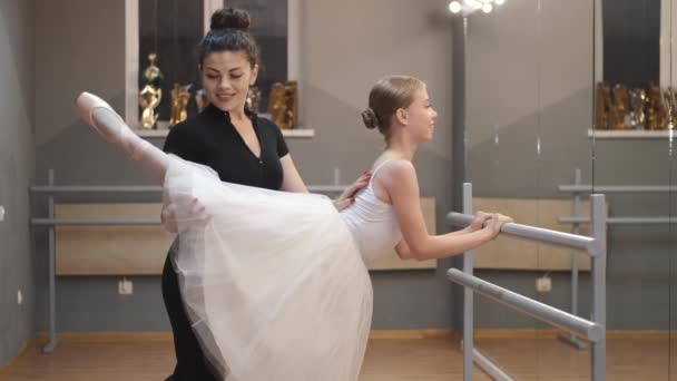 Ballet leraar professionele ballerina helpen meisje trainen in de buurt van de barre — Stockvideo