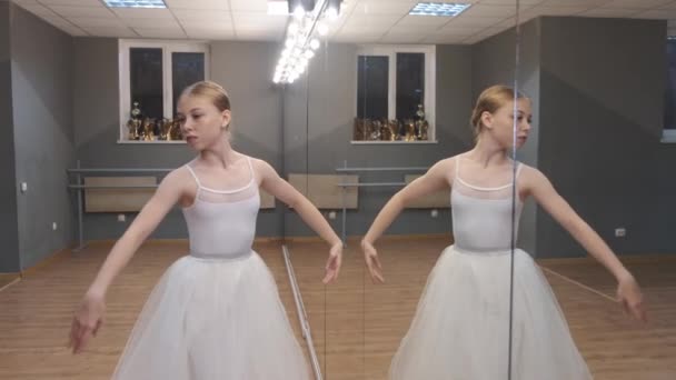 Fiatal balerina csinos ruhában gyakorol egy stúdióban — Stock videók