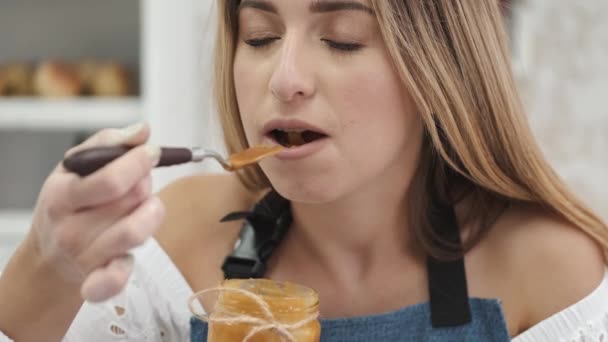 Close up jovem na cozinha comer mel de jarro com colher e desfrutar da refeição — Vídeo de Stock