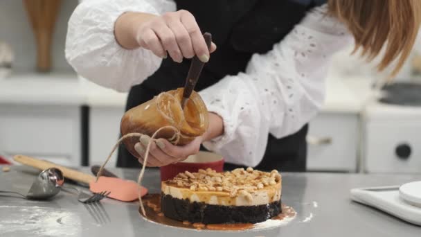 A női cukrász tortát készít és kesudióval díszíti. — Stock videók