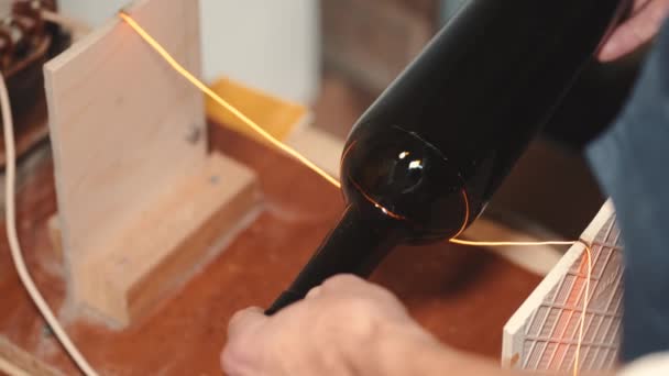 Ремесленник режет верхнюю часть пивной бутылки инструментом — стоковое видео