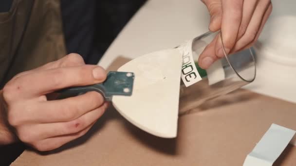 Homem colando o adesivo crativo em um vidro feito à mão em uma oficina — Vídeo de Stock