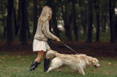Bir kadın sonbahar ormanında bir köpekle yürüyor.