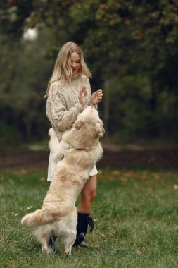 Bir kadın sonbahar ormanında bir köpekle yürüyor.