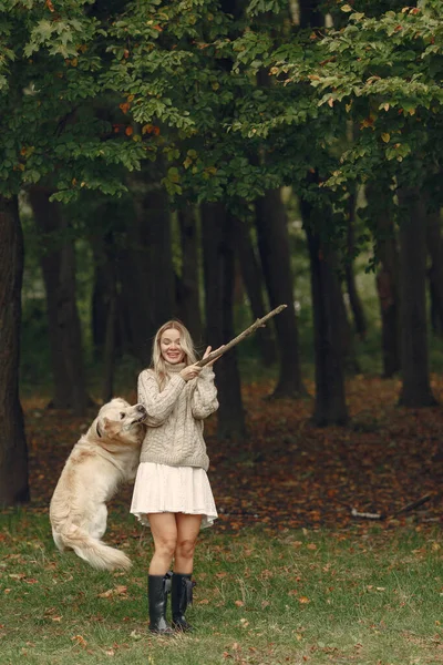 Mulher caminha na floresta de outono com um cão — Fotografia de Stock