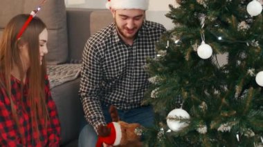 Noel ağacının altında oturan neşeli çift hediyelerini açıyor.