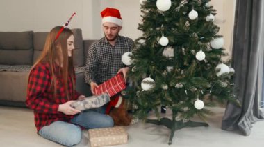 Noel ağacının altında oturan neşeli çift hediyelerini açıyor.