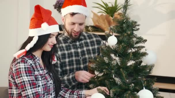 Праздничная пара украшает елку вместе дома — стоковое видео